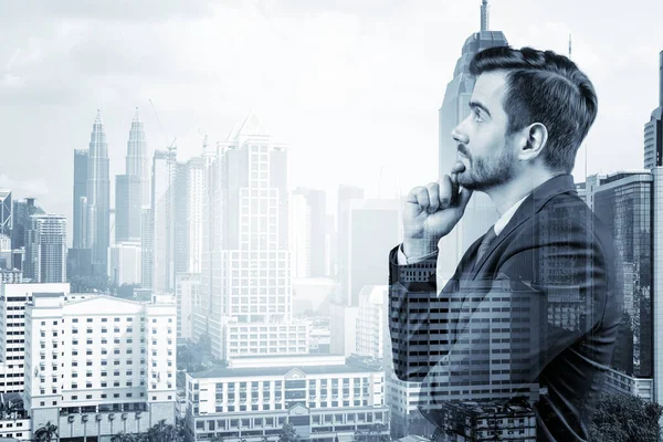 Joven hombre de negocios guapo en traje con la mano en la barbilla pensando cómo tener éxito, nuevas oportunidades de carrera, MBA. Kuala Lumpur en el fondo. Doble exposición. — Foto de Stock
