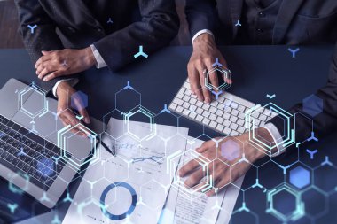 İki araştırma ve geliştirme uzmanı, işi geliştirmek için yazılım geliştirmeye yeni bir yaklaşım geliştirmek için proje üzerinde çalışıyor. Masanın üzerinde belgeyle birlikte teknolojik simgeler.