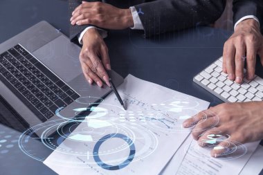 İki araştırma ve geliştirme uzmanı, işi geliştirmek için yazılım geliştirmeye yeni bir yaklaşım geliştirmek için proje üzerinde çalışıyor. Masanın üzerinde belgeyle birlikte teknolojik simgeler.