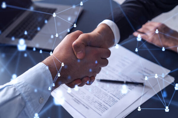 Recruitment concept to hiring of a new talented specialists for international company. Handshake to sign in of employment agreement. Social media hologram icons over the table with documents.