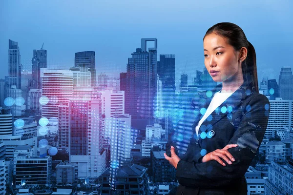 Attractive young Asian HR director at international company is thinking about recruitment of highly qualified specialists. Women in business concept. Social media hologram icons over Bangkok.