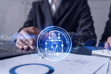 Uluslararası şirketin siber güvenliğini sağlamak için projede çalışan iki iş adamı ve kadın. Hologram simgelerini dokümanlarla masaya kilitle. Resmi kıyafet. Çalışma Alanı.