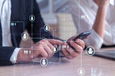 Resmi olarak pazarda çalışan iki insan kaynakları uzmanı uluslararası danışmanlık şirketinde yeni stajyerler bulmak için telefon kullanıyor. Sosyal ağ ve ortam hologramı simgeleri.