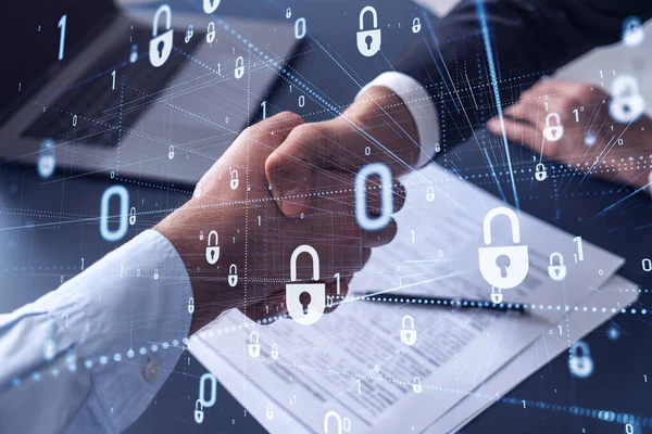 Håndtryk af to forretningsmænd, der indgår kontrakten for at beskytte cybersikkerhed i det internationale selskab. Padlock Hologram ikoner over bordet med dokumenter. - Stock-foto