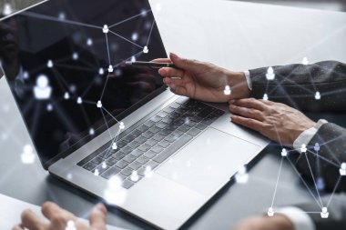 İki İK uzmanı, uluslararası danışmanlık şirketindeki stajyerlik programını hızlandırmak için dizüstü bilgisayar kullanarak işe alım pazarını inceliyor. Sosyal ağ hologram simgeleri.