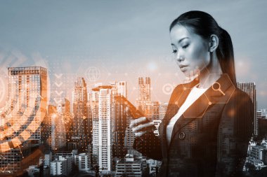 Akıllı telefonu araştırma ve geliştirme bölümündeki sorunları çözmek için modern bir araç olarak kullanan çekici Asyalı iş kadını. Bangkok üzerinde Fintech hologram simgeleri.