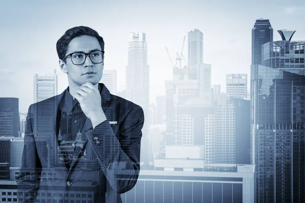 Joven hombre de negocios guapo en traje y gafas soñando con nuevas oportunidades de carrera después de la graduación del MBA. Singapur en segundo plano. Doble exposición. — Foto de Stock