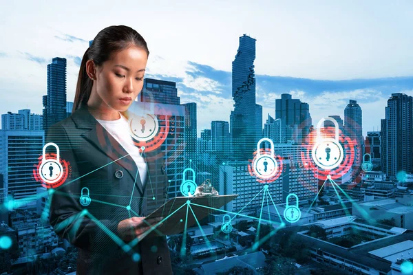 Attractive Asian cybersecurity developer explores her notes from day planner to protect clients confidential information. IT lock icons over Bangkok city background.