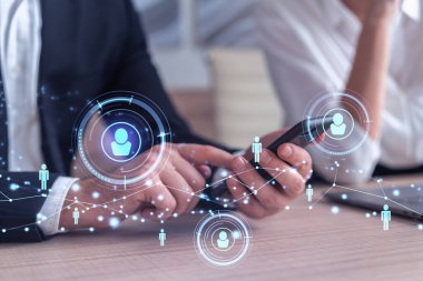 Resmi olarak pazarda çalışan iki insan kaynakları uzmanı uluslararası danışmanlık şirketinde yeni stajyerler bulmak için telefon kullanıyor. Sosyal ağ ve ortam hologramı simgeleri.