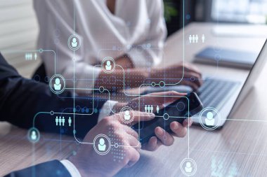 Resmi olarak pazarda çalışan iki insan kaynakları uzmanı uluslararası danışmanlık şirketinde yeni stajyerler bulmak için telefon kullanıyor. Sosyal ağ ve ortam hologramı simgeleri.