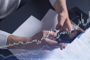 Elinde akıllı bir telefon tutan tüccar doğru yatırım çözümlerine ulaşmak için borsayı araştırıyor. İnternet ticareti ve zenginlik yönetimi kavramı. Hologram Forex grafiği yakın çekim üzerine.