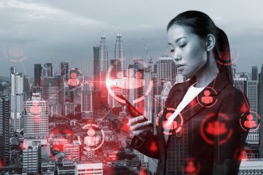 Uluslararası şirketteki çekici Asyalı İK müdürü akıllı telefon kullanarak adam toplamak için yüksek nitelikli uzmanlar arıyor. Kuala Lumpur üzerinde sosyal medya hologramı simgeleri.