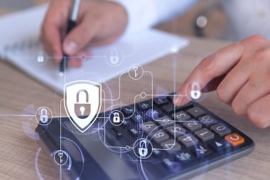 Bir iş adamı, hesap makinesi kullanarak siber güvenlik korumasında risk olasılığını hesaplıyor. Çalışma masasının üzerine asma kilit hologramı simgeleri. Resmi giysi.