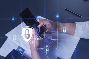 Bir programcı, bir siber güvenliği hacker saldırılarından korumak ve müşterilerinin gizli verilerini kaydetmek için akıllı telefonuyla internete giriyor. Yazan ellerin üzerine asma kilit hologramı simgeleri.