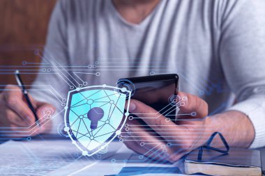 Sıradan bir iş adamı siber güvenlikte risk olasılığını önlemek için sözleşmeyi imzalıyor. Telefonu kontrol ediyorum. Çalışma masasının üzerine asma kilit hologramı simgeleri.