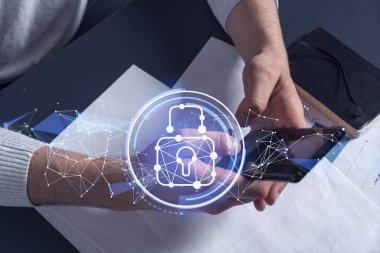 Bir programcı, bir siber güvenliği hacker saldırılarından korumak ve müşterilerinin gizli verilerini kaydetmek için akıllı telefonuyla internete giriyor. Yazan ellerin üzerine asma kilit hologramı simgeleri.