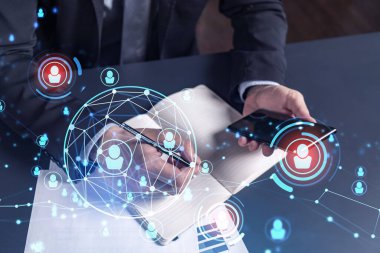 İnsan Kaynakları uzmanı, yeni adaylarla ilgili notlar alıyor. İşe alım sürecinde uluslararası bir ağ oluşturmak için. Akıllı telefondan sosyal medya bağlantılarını kontrol ediyorum. Hologram simgeleri. Resmi takım elbise