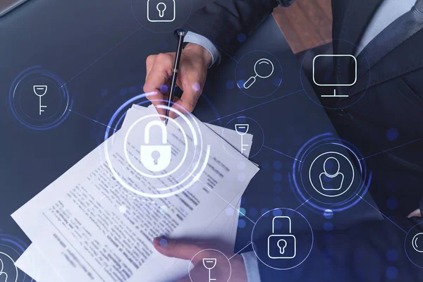 A businessman in formal wear signing the contract to prevent probability of risks in cyber security. Padlock Hologram icons over the working desk.