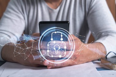 Bir programcı, bir siber güvenliği hacker saldırılarından korumak ve müşterilerinin gizli verilerini kaydetmek için akıllı telefonuyla internete giriyor. Yazan ellerin üzerine asma kilit hologramı simgeleri.