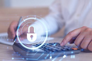 Bir iş adamı, hesap makinesi kullanarak siber güvenlik korumasında risk olasılığını hesaplıyor. Çalışma masasının üzerine asma kilit hologramı simgeleri. Resmi giysi.