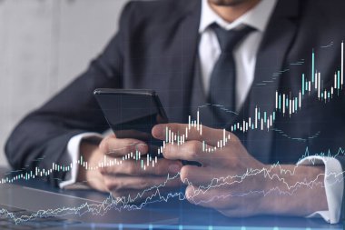 Elinde akıllı bir telefon tutan tüccar doğru yatırım çözümlerine ulaşmak için borsayı araştırıyor. İnternet ticareti ve zenginlik yönetimi kavramı. Hologram Forex grafiği yakın çekim üzerine.
