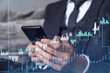 Elinde akıllı bir telefon tutan tüccar doğru yatırım çözümlerine ulaşmak için borsayı araştırıyor. İnternet ticareti ve zenginlik yönetimi kavramı. Hologram Forex grafiği yakın çekim üzerine.