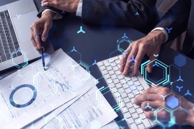 İki araştırma ve geliştirme uzmanı, işi geliştirmek için yazılım geliştirmeye yeni bir yaklaşım geliştirmek için proje üzerinde çalışıyor. Masanın üzerinde belgeyle birlikte teknolojik simgeler.