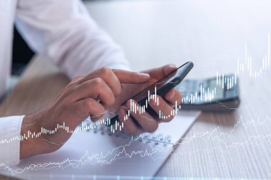 Elinde akıllı bir telefon tutan tüccar doğru yatırım çözümlerine ulaşmak için borsayı araştırıyor. İnternet ticareti ve zenginlik yönetimi kavramı. Hologram Forex grafiği yakın çekim üzerine.