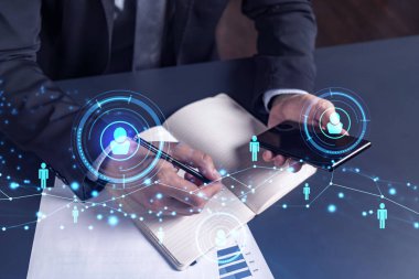 İnsan Kaynakları uzmanı, yeni adaylarla ilgili notlar alıyor. İşe alım sürecinde uluslararası bir ağ oluşturmak için. Akıllı telefondan sosyal medya bağlantılarını kontrol ediyorum. Hologram simgeleri. Resmi takım elbise