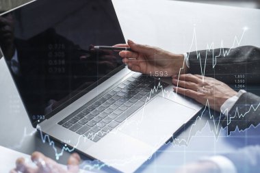 İki tüccar dizüstü bilgisayar kullanarak borsa davranışlarını tahmin etmek için tarihi verileri araştırıyor. İnternet ticareti konsepti. Eski ve finansal hologram şeması. Tahmin ve planlama.