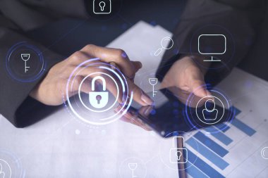 Resmi olarak çalışan bir iş kadını, siber güvenlikte risk olasılığını önlemek için sözleşmeyi imzalamak için telefonu kontrol ederken giyer. Çalışma masasının üzerine asma kilit hologramı simgeleri.