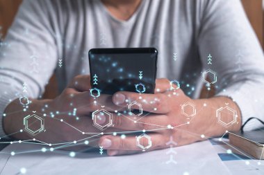 Programcı elinde akıllı bir telefon tutuyor ve tamamen yeni bir hizmet sunmak için yenilikçi bir uygulamayı test ediyor. Yakın çekim. Hologram teknik grafikleri. Dev takım kavramı.