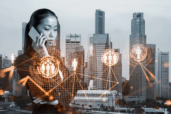 Attractive Asian businesswoman processing conference call to develop social media marketing strategy to achieve business goals. Hologram icons over Singapore background.