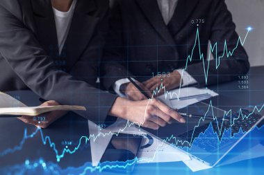 Borsa davranışlarını tahmin etmek için tarihi verileri araştıran iki tüccar. Ticaret dünyasındaki kadınlar. Belgenin olduğu masanın üzerinde eski ve finansal hologram şeması.