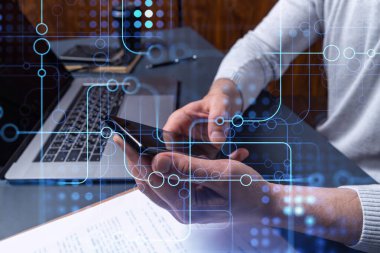 Programcı elinde akıllı bir telefon tutuyor ve tamamen yeni bir hizmet sunmak için yenilikçi bir uygulamayı test ediyor. Yakın çekim. Hologram teknik grafikleri. Dev takım kavramı.