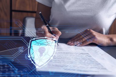Sıradan giyinen bir iş kadını siber güvenlikte risk olasılığını önlemek için sözleşmeyi imzalıyor. Çalışma masasının üzerine asma kilit hologramı simgeleri.
