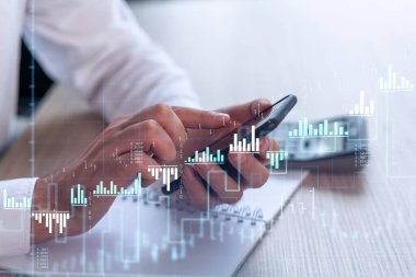 Elinde akıllı bir telefon tutan tüccar doğru yatırım çözümlerine ulaşmak için borsayı araştırıyor. İnternet ticareti ve zenginlik yönetimi kavramı. Hologram Forex grafiği yakın çekim üzerine.