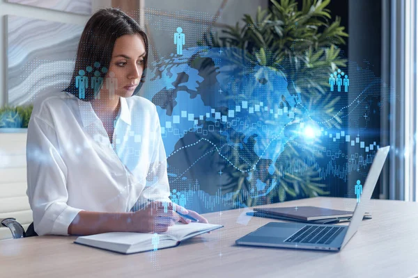 Attraktiv forretningskvinde i hvid skjorte på arbejdspladsen arbejder med laptop til at ansætte nye medarbejdere til international business rådgivning. HR, hologramikoner til sociale medier over kontorbaggrund - Stock-foto