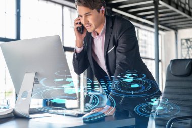 Takım elbiseli iş adamının, iş sürecinde yeni teknolojiler ima ederek gelişimi optimize etmek için konferans çağrısı var. Ofis arka planında panoramik pencereli yüksek teknoloji hologramı ve bağlantıları var