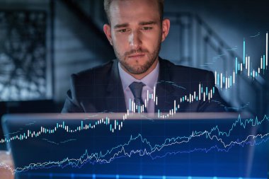 İş yerindeki takım elbiseli yakışıklı işadamı şirket finans fonundaki ticaret stratejisini optimize etmek için dizüstü bilgisayarla çalışıyor. Ofis arkaplanı üzerinde eski grafik hologramı