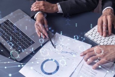İki araştırma ve geliştirme uzmanı, işi geliştirmek için yazılım geliştirmeye yeni bir yaklaşım geliştirmek için proje üzerinde çalışıyor. Masanın üzerinde belgeyle birlikte teknolojik simgeler.