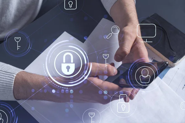 Bir programcı, bir siber güvenliği hacker saldırılarından korumak ve müşterilerinin gizli verilerini kaydetmek için akıllı telefonuyla internete giriyor. Yazan ellerin üzerine asma kilit hologramı simgeleri.