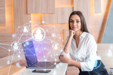 İş yerindeki beyaz gömlekli çekici iş kadını uluslararası iş danışmanlığı için yeni çalışanlar arıyor. İK ve sosyal medya hologram simgeleri ofis arka planında