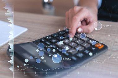 Borsa davranışlarını tahmin etmek için tarihi verileri hesaplayan bir kadın tüccar. İnternet ticareti konsepti. Masa ve hesap makinesinin üzerinde eski ve finansal hologram şeması.