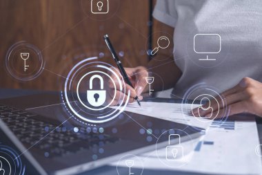 Sıradan giyinen bir iş kadını siber güvenlikte risk olasılığını önlemek için sözleşmeyi imzalıyor. Çalışma masasının üzerine asma kilit hologramı simgeleri.