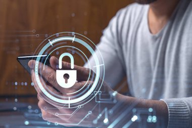 Bir programcı, bir siber güvenliği hacker saldırılarından korumak ve müşterilerinin gizli verilerini kaydetmek için akıllı telefonuyla internete giriyor. Yazan ellerin üzerine asma kilit hologramı simgeleri.