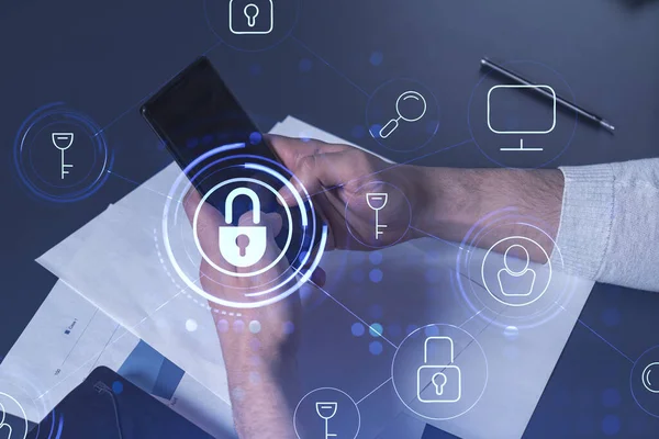 Bir programcı, bir siber güvenliği hacker saldırılarından korumak ve müşterilerinin gizli verilerini kaydetmek için akıllı telefonuyla internete giriyor. Yazan ellerin üzerine asma kilit hologramı simgeleri.