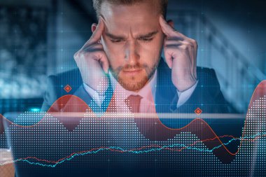 İş yerindeki takım elbiseli yakışıklı işadamı şirket finans fonundaki ticaret stratejisini optimize etmek için dizüstü bilgisayarla çalışıyor. Ofis arkaplanı üzerinde eski grafik hologramı
