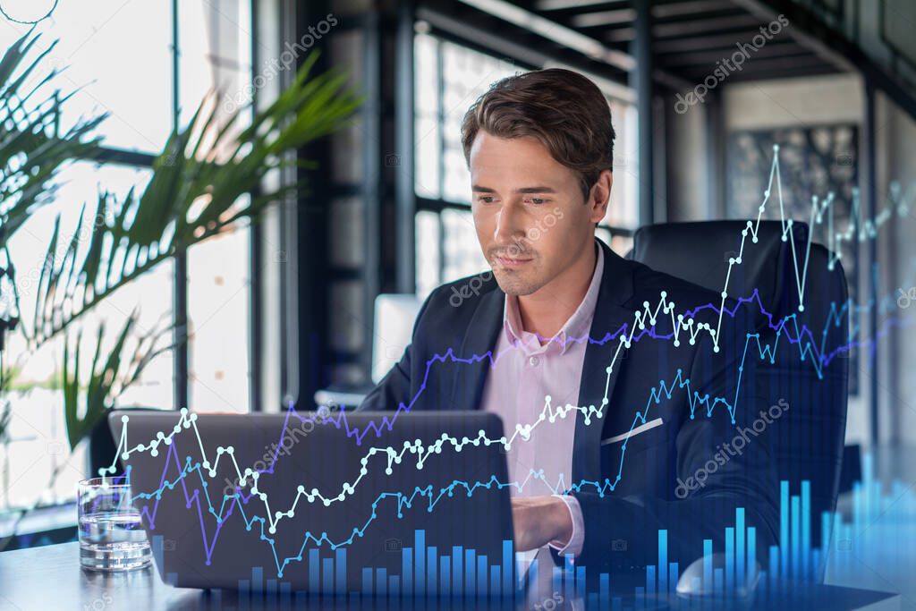 Handsome businessman in suit at workplace working with laptop to optimize trading strategy at corporate finance fund. Forex chart hologram over office background