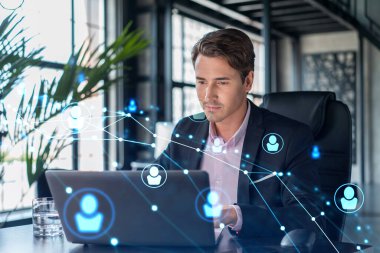 İş yerindeki takım elbiseli yakışıklı işadamı uluslararası iş danışmanlığı için yeni çalışanlar arıyor. İK ve sosyal medya hologram simgeleri ofis arka planında